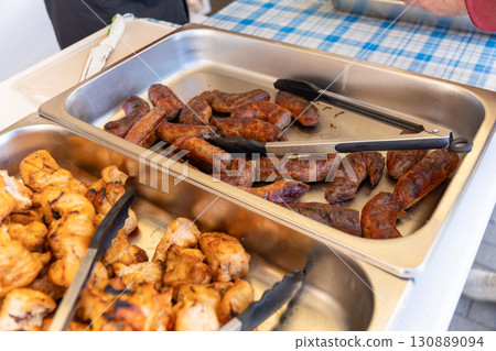 Grilled sausages and kebabs on serving trays at a Swedish table buffet. 130889094