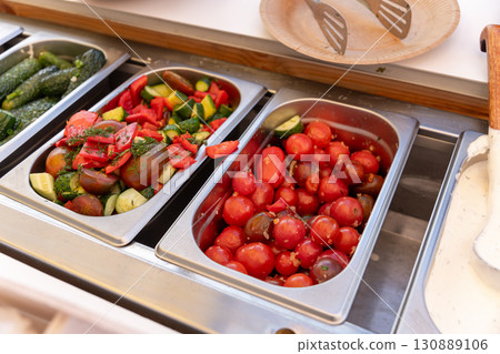 Fresh vegetable salads, pickled cucumbers and tomatoes, and other snacks on a buffet table. Fresh vegetable salads, pickled cucumbers and tomatoes, and other snacks on a buffet table. 130889106