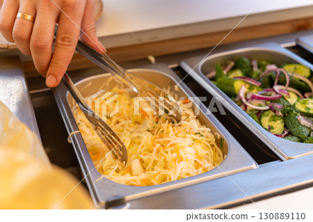 A visitor serves sauerkraut salad from a buffet A visitor serves sauerkraut salad from a buffet 130889110