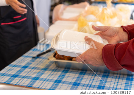 Hands exchanging takeout container at outdoor cafe. Hands exchanging takeout container at outdoor cafe. 130889117
