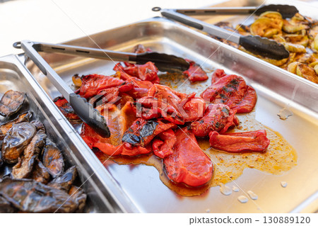 Baked bell peppers on a charcoal grill, served on a platter for a buffet. 130889120