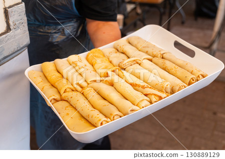 A chef proudly presents a tray of golden, freshly made cottage cheese pancakes 130889129
