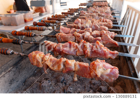 Sizzling skewers of marinated meat grilling over hot coals 130889131
