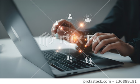 A person is working at a laptop with virtual icons symbolizing technology. A person is working at a laptop with virtual icons symbolizing technology. 130889181