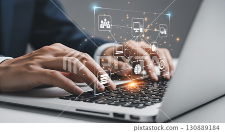 A person is working at a laptop with virtual icons symbolizing technology. 130889184