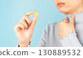 Woman taking medical lozenges with honey lemon flavored for relief sore throat, irritating cough and mouth pain. Close up of female feeling sick and cold over light blue backgroud. Health care. 130889532