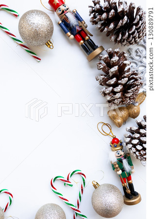 Festive arrangement with nutcrackers, glittery ornaments, and pinecones on white background 130889791