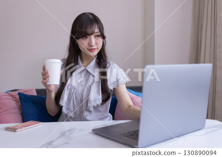 A Japanese woman working on a PC in the living room with a mug in her hand A Japanese woman working on a PC in the living room with a mug in her hand 130890094
