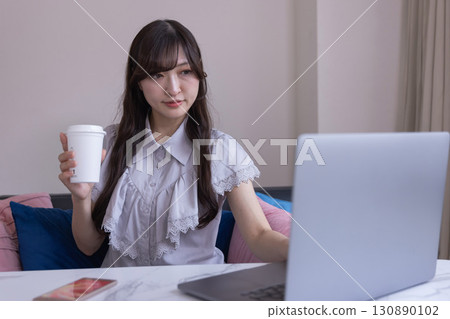 A Japanese woman working on a PC in the living room with a mug in her hand A Japanese woman working on a PC in the living room with a mug in her hand 130890102