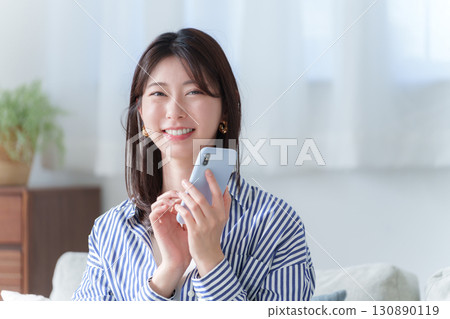 使用智慧型手機的微笑年輕女子 130890119