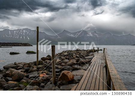 Wooden Pier At Rainy Weather In Fjord With Snowy Mountains On Senja Island In Mefjordvaer In Norway Wooden Pier At Rainy Weather In Fjord With Snowy Mountains On Senja Island In Mefjordvaer In Norway 130890438