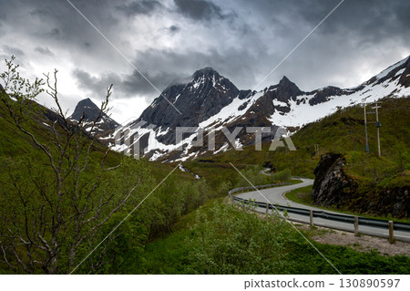 Steep And Curvy Mountain Road With Snowy Mountain Peaks On Senja Island In Norway 130890597