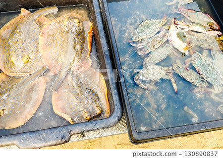 Seafood delicacies. Freshly caught stingrays and crabs are on sale at the local fish market on the sandy beach, showcasing the day's ocean riches ready to attract seafood lovers 130890837