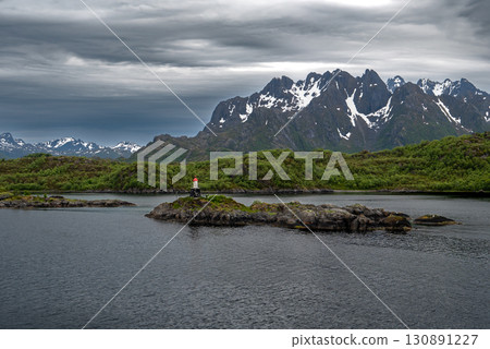 Coastal Landscape With Lighthouse And Snowy Mountains Near Stokmarknes At The Lofoten In Norway Coastal Landscape With Lighthouse And Snowy Mountains Near Stokmarknes At The Lofoten In Norway 130891227