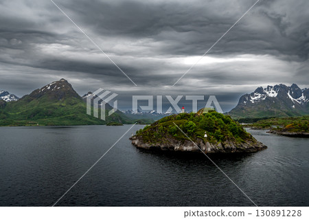 Coastal Landscape With Lighthouse And Snowy Mountains Near Stokmarknes At The Lofoten In Norway 130891228