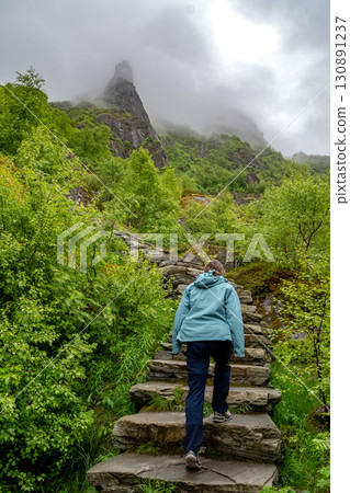 Woman Hiking On Devils Stairs To Djevelporten The Devils Stone In Svolvaer On Lofoten Islands In Norway Woman Hiking On Devils Stairs To Djevelporten The Devils Stone In Svolvaer On Lofoten Islands In Norway 130891237