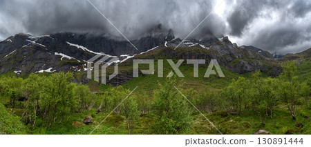 Green Valley With Snowy Mountains Near Nusfjord On Lofoten Islands In Norway Green Valley With Snowy Mountains Near Nusfjord On Lofoten Islands In Norway 130891444