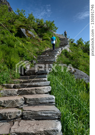 Woman Hiking On Steep Sherpy Stairs On Reinebringen Trail On Lofoten Islands In Norway Woman Hiking On Steep Sherpy Stairs On Reinebringen Trail On Lofoten Islands In Norway 130891746