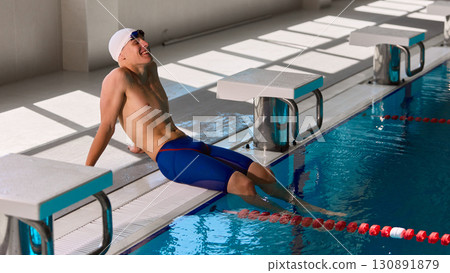 Swimmer relaxing on poolside with smile after training session in sunlight 130891879
