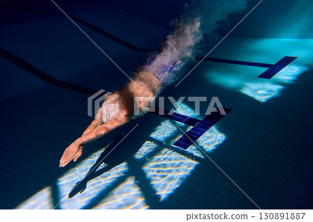 Underwater swimmer with strong push creating bubbles in pool 130891887
