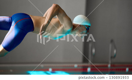 Male swimmer in close-up streamlined dive motion during professional start 130891933
