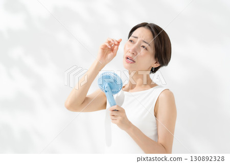 A woman who cools down with a handy fan 130892328