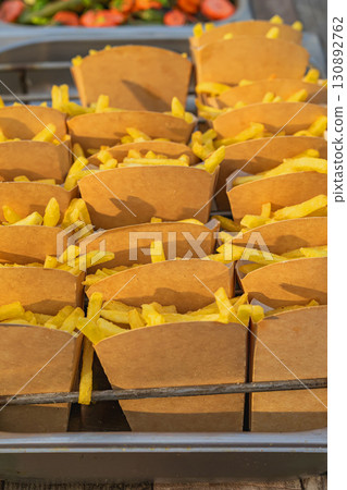 French Fries in Boxes. Multiple servings of golden French fries packed in brown paper boxes. Concept of fast food, street snack, casual dining convenience French Fries in Boxes. Multiple servings of golden French fries packed in brown paper boxes. Concept of fast food, street snack, casual dining convenience 130892762