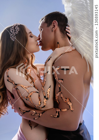 Romantic embrace between a couple with artistic body paint and angelic wings 130893145