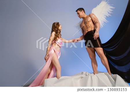 Couple in fantasy attire posing together on a creative stage setting 130893153