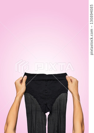 female hands holding black nylon pantyhose on pink background. female hands holding black nylon pantyhose on pink background. 130894085