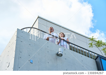A wealthy middle-aged couple standing on the balcony A wealthy middle-aged couple standing on the balcony 130894267