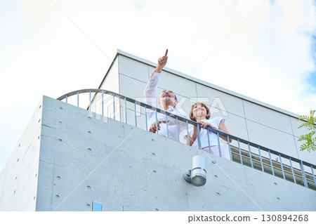 A wealthy middle-aged couple standing on the balcony A wealthy middle-aged couple standing on the balcony 130894268