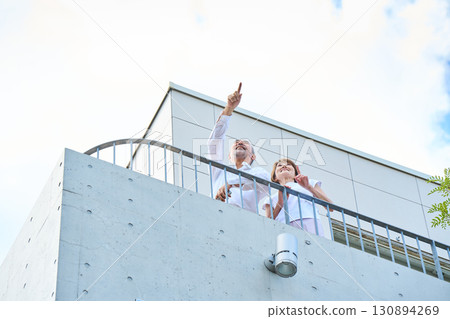 A wealthy middle-aged couple standing on the balcony 130894269