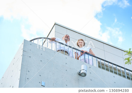 A wealthy middle-aged couple standing on the balcony 130894280