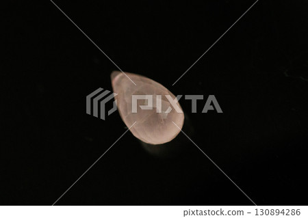 Morganite briolette cut gemstone against a black background 130894286