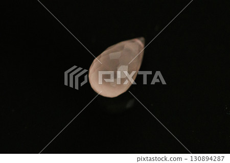 Morganite briolette cut gemstone against a black background 130894287