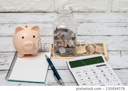 Image of a piggy bank, a jar of coins, a calculator and a notebook with money 130894576