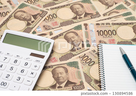 A calculator, notebook, and pen placed on top of a pile of 10,000 yen bills A calculator, notebook, and pen placed on top of a pile of 10,000 yen bills 130894586