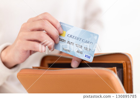 一位穿著休閒服的中年婦女從錢包裡拿出一張信用卡 130895785