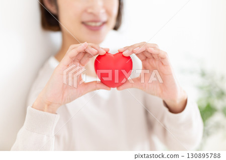 一位身著休閒服的中年婦女拿著心臟模型 130895788