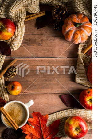 Hot drink frame, cosy autumn coffee drink, with apples and cinnamon, orange pumpkins, wooden rustic background 130896740