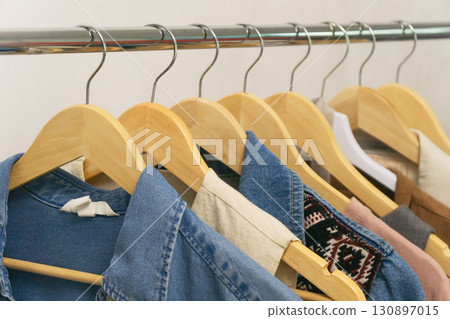 Unique styles of upcycled second-hand denim displayed on hangers in a chic boutique setting Unique styles of upcycled second-hand denim displayed on hangers in a chic boutique setting 130897015