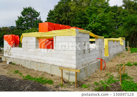 New house construction with aerated concrete blocks and protective covers on building site 130897128