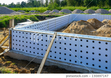 Concrete foundation with insulated formwork and soil piles at residential construction site Concrete foundation with insulated formwork and soil piles at residential construction site 130897147