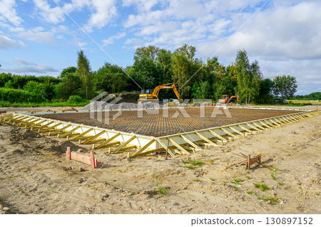 Construction site with rebar foundation and wooden formwork for concrete slab with excavators Construction site with rebar foundation and wooden formwork for concrete slab with excavators 130897152