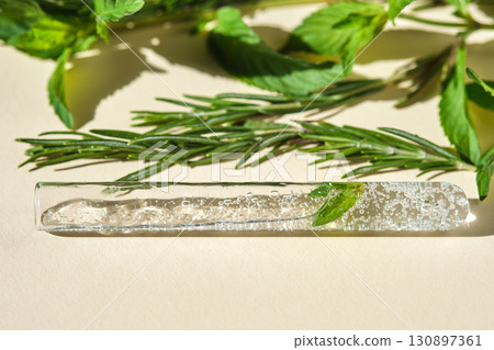 A test tube with the texture of serum or other cosmetics with mint and herbs. 130897361