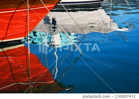Reflection of moored yachts in the clear blue water of the sea port 130897431