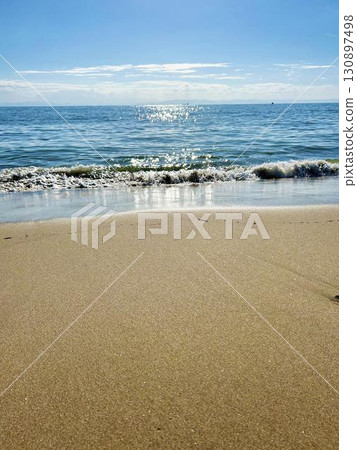 Waves crashing on the beach and a calm sky 130897498