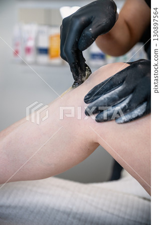 Beautician applying sugaring paste on female leg during professional hair removal procedure Beautician applying sugaring paste on female leg during professional hair removal procedure 130897564