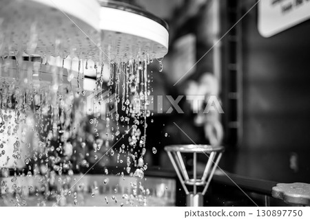 Water droplets cascade from a showerhead in a serene spa setting during a tranquil moment 130897750